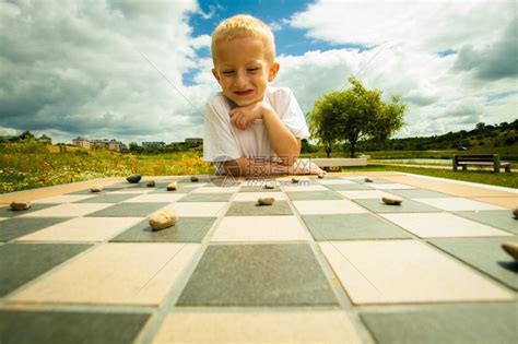 小男孩聪明的在公园户外玩跳棋游戏高清图片下载-正版图片304035925-摄图网