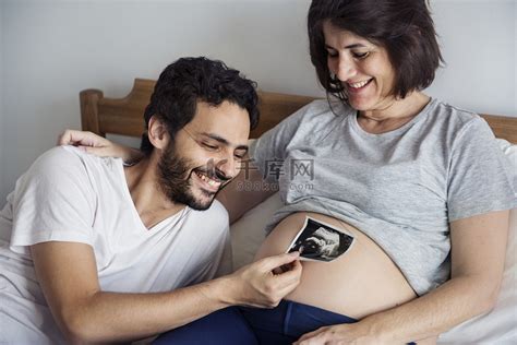 丈夫在怀孕妻子腹部附近拍摄胎儿照片高清摄影大图-千库网