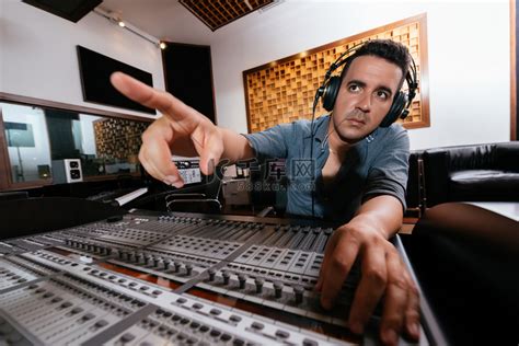 男性音响工程师在混音控制台、后视图、背景录音室内部。高清摄影大图-千库网