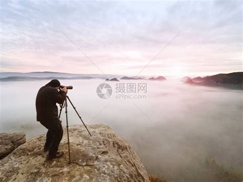 摄影师用取景器取景摄影爱好者在岩石山顶享受秋季大自然的作品梦幻般的风景高清图片下载-正版图片507440214-摄图网