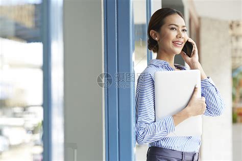 户外拿着笔记本电脑打电话的年轻女子高清图片下载-正版图片502178187-摄图网