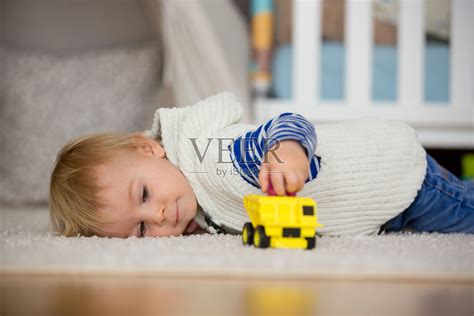 可爱的蹒跚学步的男孩，在家里的儿童房玩汽车玩具，儿童幸福的概念照片摄影图片_ID:334604958-Veer图库