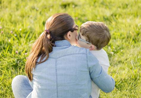 mignon fils baiser sa mère assise dans un champ — Photographie doble ...
