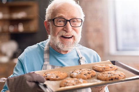 穿着围裙的年长男子拿着美味饼干盘子在高清图片下载-正版图片502717495-摄图网