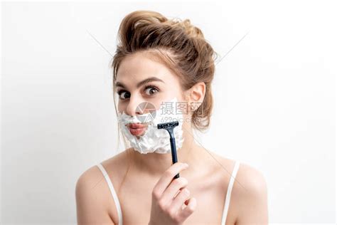 美丽的年轻caucasian女人用剃刀刮脸的白色背景高清图片下载-正版图片506639944-摄图网