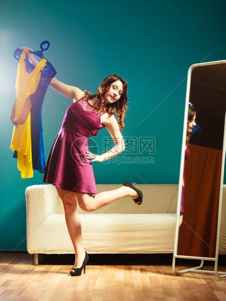 时装和购物女人准备参加派对试着穿衣服迷人的年轻女看着镜子站在服装店里高清图片下载-正版图片304113826-摄图网