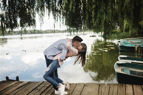 情侣在湖边木桥上弯腰接吻高清图片下载-正版图片303673247-摄图网