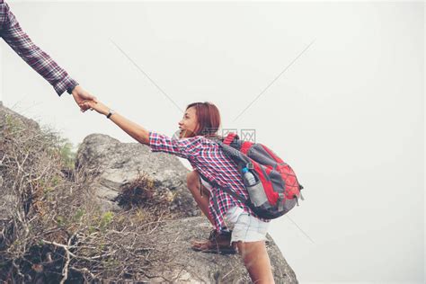 年轻的时髦男人帮助女人爬山高清图片下载-正版图片502705595-摄图网