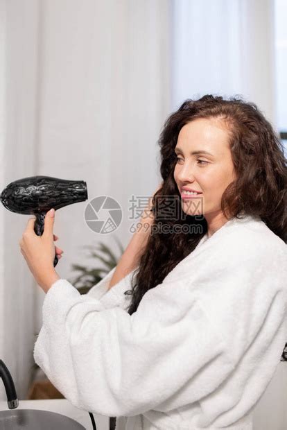 漂亮的年轻微笑的女士与头发干洗机照顾她的黑长卷毛在高清图片下载-正版图片506349530-摄图网