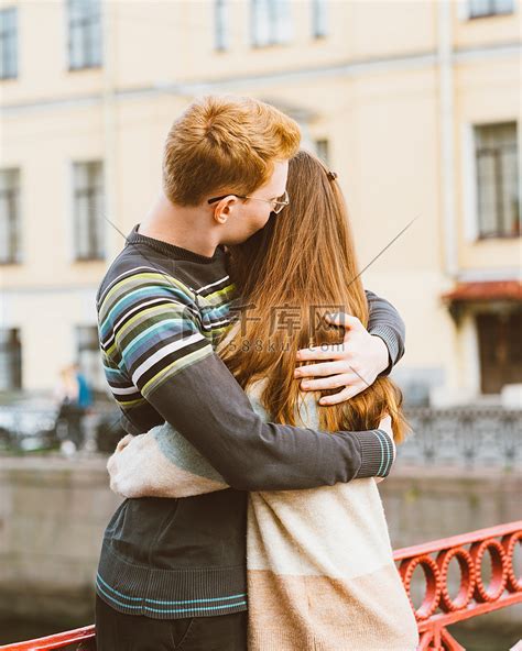 红头发的男人亲吻了一个女人的头顶，一个穿着毛衣的男孩安慰着一个长着深色浓密头发的女孩高清摄影大图-千库网