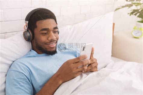 使用耳机听音乐或观看在线流传广播躺在床上复制空间的黑高清图片下载-正版图片503588637-摄图网