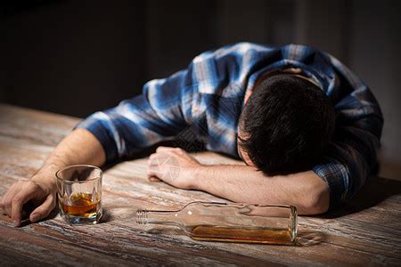 酒精中,酒精成瘾人的男酒精与瓶子喝白兰地桌子上晚上醉汉晚上桌子上喝酒高清图片下载-正版图片300156127-摄图网