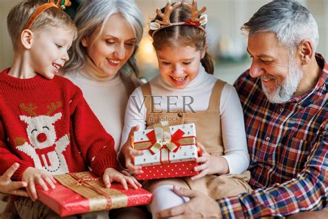 在圣诞节的早晨，慈爱的老祖父母给快乐的孙子孙女们送去包装好的圣诞礼物照片摄影图片_ID:412249736-Veer图库