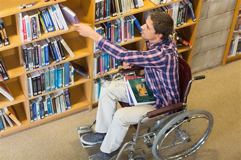 在图书馆里挑选书本的轮椅男高清图片下载-正版图片321926238-摄图网