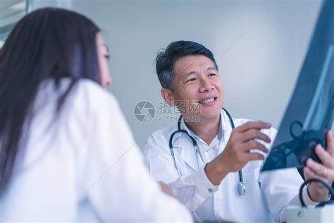 在一家医院里，医生们正在向一位躺在病床上的女病人询问并解释病情。(4 k的分辨率)视频素材_ID:VCG42N1127344389-VCG.COM