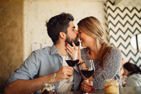 英俊的男子亲吻他的女朋友在鼻子。夫妇喝葡萄酒咖啡馆和庆祝情人节.高清摄影大图-千库网