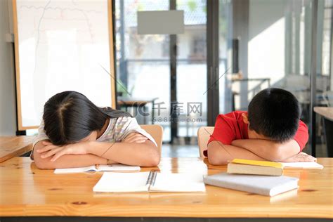 疲惫不堪的女男孩学生在图书馆学习艰苦考试后睡觉高清摄影大图-千库网