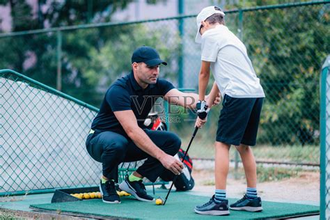 高尔夫课程。高尔夫教练给一个小男孩上游戏课。照片摄影图片_ID:354893233-Veer图库