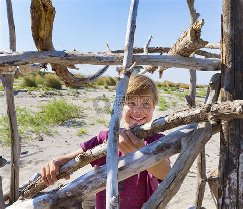 海滩上拿着浮木建造庇护所的男孩高清图片下载-正版图片501843218-摄图网