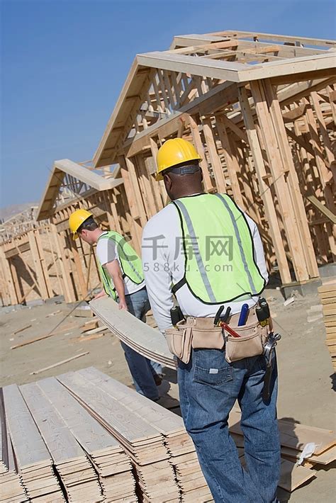 两名建筑工人在工地上搬运木板包人物特写高清摄影大图-千库网