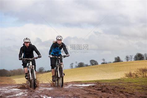 一对夫妇骑自行车穿过泥泞的水坑高清图片下载-正版图片501524060-摄图网