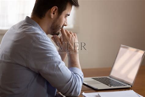 沉思的男性看着笔记本电脑屏幕，思考着做决定照片摄影图片_ID:351858121-Veer图库