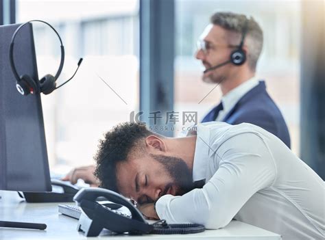 懒惰、睡觉、疲惫的呼叫中心代理在他的桌子或办公桌上工作，过度劳累，遭受倦怠。高清摄影大图-千库网