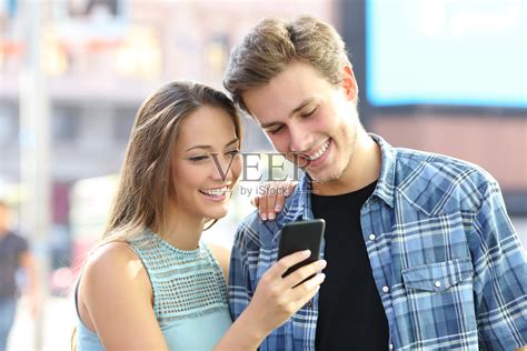幸福的夫妇在街上看手机上的内容照片摄影图片_ID:354597865-Veer图库