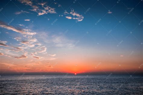 一艘船在日落时分在大海中航行高清摄影大图-千库网