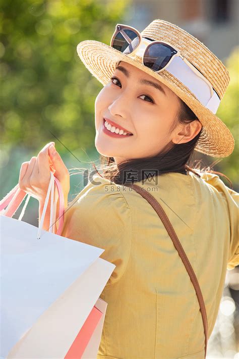 拿着购物袋的青年女人回眸一笑高清摄影大图-千库网