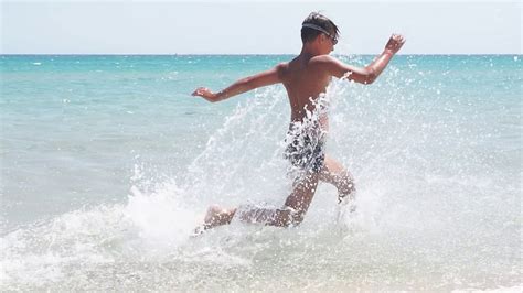 慢镜头拍摄的亚洲男孩在沙滩上享受和玩海和沙子视频素材_ID:VCG42N1368630557-VCG.COM