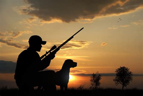 狩猎场景:一群猎人背着背包，背着猎枪，在阴天的狩猎季节穿过乡间田野照片摄影图片_ID:159678478-Veer图库