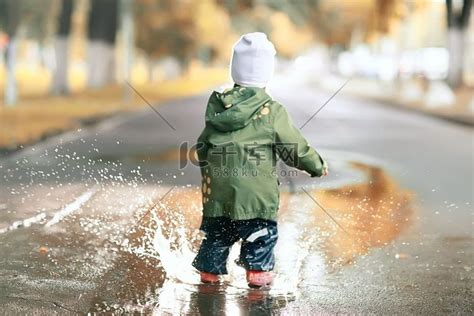 女孩在秋天公园的水坑里跑来跑去，童年游戏高清摄影大图-千库网