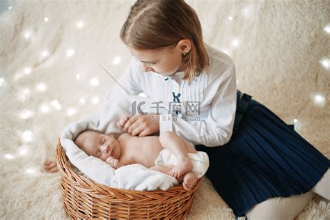 快乐的女孩看着她刚出生的妹妹。高清摄影大图-千库网