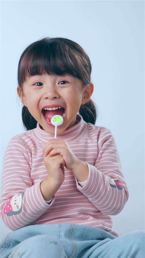 一个小女孩在舔棒棒糖照片摄影图片_ID:420669221-Veer图库