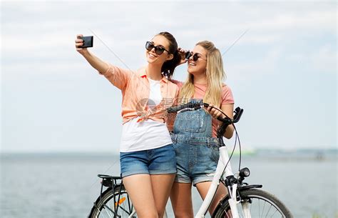 休闲,技术友谊的快乐微笑的十几岁女孩朋友骑自行车自拍智能手机海边夏天夏天自行车自拍的十几岁女孩高清图片下载-正版图片300064273-摄图网