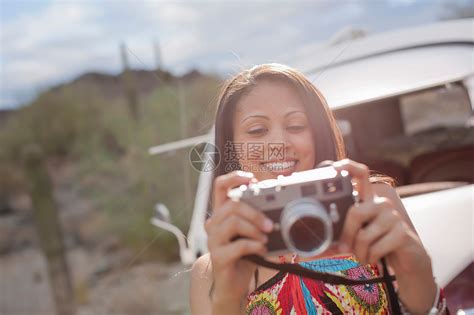 年轻女子在路上旅行时拿着相机微笑高清图片下载-正版图片501833325-摄图网
