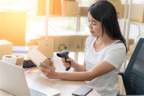 亚洲自由职业女在家工作并通过在线互联网创办小型企业家SME年轻女子正在扫描包装盒中的条形码高清图片下载-正版图片504485366-摄图网