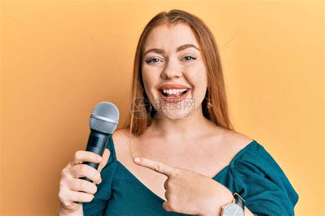 年轻漂亮的红发女人用麦克风唱歌高清图片下载-正版图片504378247-摄图网