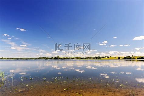 湖水平静，另一边是树林，天空湛蓝。景观壁纸湖泊高清摄影大图-千库网