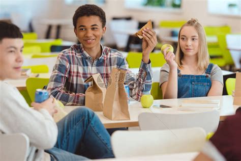 高中学生在食堂吃午餐时聊天的多种族多民族群高清图片下载-正版图片503582827-摄图网