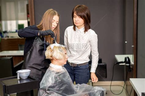 年轻女实习生在理发店的专业美发师监督下学高清图片下载-正版图片506741792-摄图网