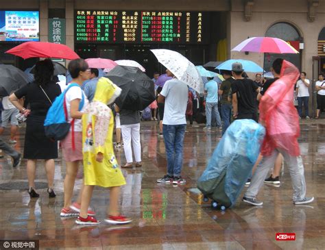 北京站迎暑期客流高峰 旅客冒雨打伞赶火车