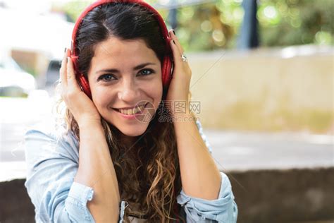 快乐的年轻女子在街上用耳机听音乐夏季生活方式高清图片下载-正版图片303514795-摄图网
