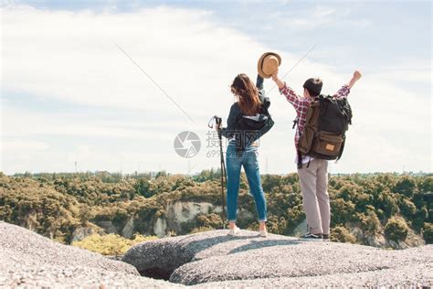 岩石一对夫妇在爬山后举起双手成功地徒步登山到顶或峰旅行和夏季概念一种冒险高清图片下载-正版图片308006982-摄图网