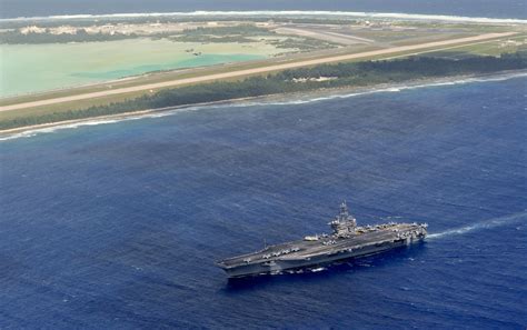 美军核动力航母打击群大秀肌肉，舰载机编队伴飞跨过岛礁