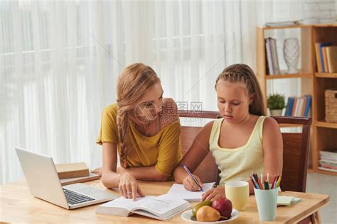 白人母女在桌边用书做家务女学生用钢笔高清图片下载-正版图片505494280-摄图网