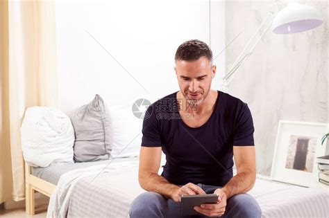 四十多岁的白人男坐在卧室的床上高清图片下载-正版图片506015024-摄图网