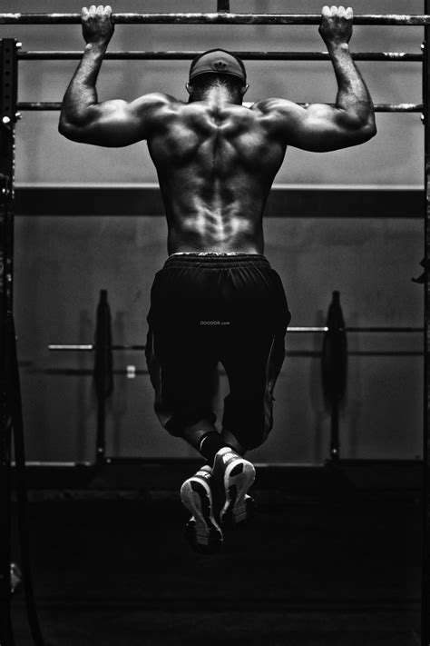 健身达人在健身房内做着引体向上姿势优美他身上的肌肉强壮有力