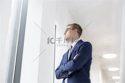 年轻体贴的商人双臂交叉站在办公室走廊里男人屏幕截图高清摄影大图-千库网